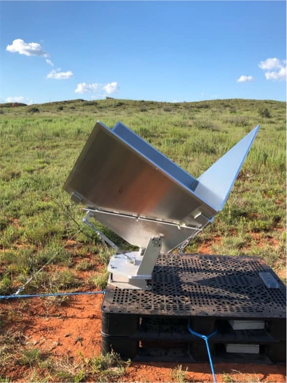 Metal corner reflector points at the sky in a grassy field